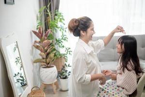 madre asiatica che taglia i capelli a sua figlia nel soggiorno di casa mentre resta a casa al sicuro dal coronavirus covid-19 durante il blocco. concetto di auto-quarantena e distanziamento sociale. foto