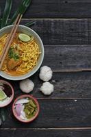 ricetta khao soi, khao soi, khao soi kai, thai noodles khao soi, pollo al curry con condimento servito su tavola di legno foto