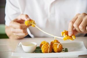 l'uomo mangerà una palla di formaggio fritta appiccicosa. la foto è focalizzata sulla palla di formaggio