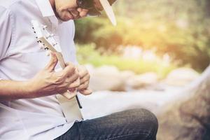 l'uomo suona l'ukulele nuovo per lo stile di vita della gente del fiume e dello strumento musicale nel concetto di natura foto