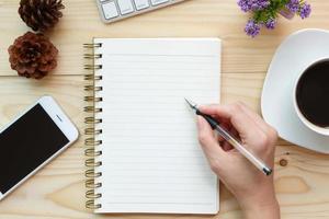 taccuino di scrittura a mano sul lavoro di scrivania in legno foto