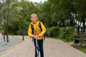 ragazzo con una felpa gialla con uno zaino sulla schiena che va a scuola. concetto di ritorno a scuola foto