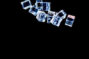 cubetti di ghiaccio su sfondo nero. ghiaccio che cade su uno sfondo nero da utilizzare come illustrazione in un progetto foto