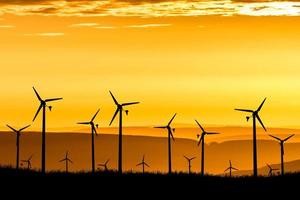 le turbine eoliche producono elettricità la sera. tramonto, silhouette, mulini a vento, energia pulita la sera. alternativa di concetto rinnovabile ed energia pulita ed eolica foto