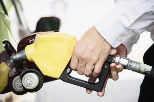 uomo che mette benzina nella sua auto in una stazione di servizio della pompa foto