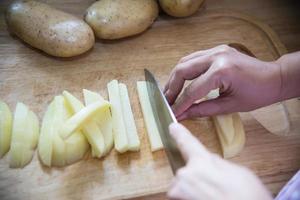 persone che cucinano patate fresche che preparano il cibo in cucina - concetto di cottura delle patate foto