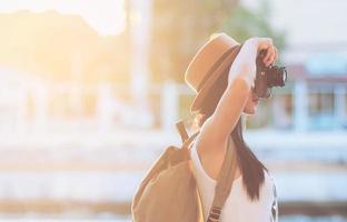 macchina fotografica di ripresa della donna di viaggio turistico mentre cammina su una strada - concetto di viaggio dello zaino della via foto