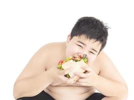 un ragazzo grasso sta mangiando felicemente un panino. foto