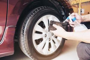 l'uomo di servizio sta incerando il garage dei pneumatici dell'auto - concetto di servizio di manutenzione dell'auto foto