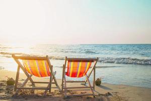 coppia relax sedia sulla spiaggia di sabbia con caldo tramonto - vacanza nel bellissimo mare concetto di natura