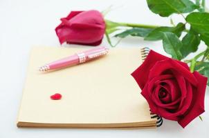 rosa rossa e penna rosa con taccuino su sfondo bianco - concetto di e-card amore e fiore foto