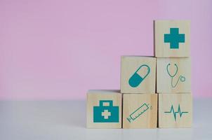 blocco di cubi di legno con il simbolo medico dell'auto sanitaria di assicurazione sullo sfondo rosa e lo spazio della copia. foto