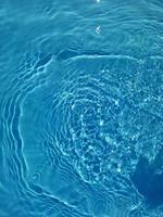 sfocatura sfocata acqua blu che brilla nel mare. sfondo di dettagli d'acqua increspata. la superficie dell'acqua nel mare, sullo sfondo dell'oceano. onda d'acqua sotto il fondo di struttura del mare. foto