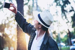 uomo asiatico con il telefono cellulare nella natura dell'albero della foresta - persone in natura primaverile e concetto di tecnologia foto