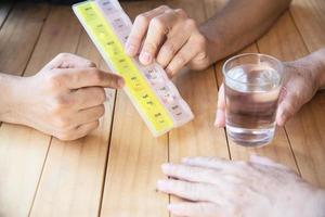 il medico assiste il paziente a mangiare correttamente la compressa di medicina nel portapillole - concetto medico delle persone foto