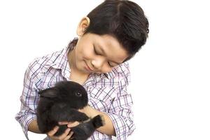 bambino asiatico che gioca con il coniglio adorabile del bambino isolato sopra bianco foto