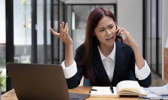 donna d'affari asiatica stressata o responsabile marketing femminile che discute al telefono con il suo collega. donna d'affari seria, infelice, insoddisfatta, pazza. foto