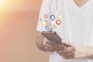 concetto di tecnologia dei social media, mano d'uomo che utilizza l'accesso smartphone alla rete online utilizza i social media per fare affari e pagamenti di marketing da casa tramite Internet. foto