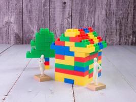 casa giocattolo multicolore in mattoni e figura bianca per il concetto di business per bambini o proprietà foto