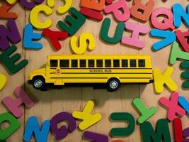 l'alfabeto in legno multicolore e scuolabus sul tavolo per l'istruzione o il concetto di bambino foto