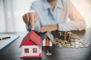 modello di casa con monete impilate, la mano d'affari sta pianificando risparmi di monete per comprare casa. concetto per scala di proprietà, mutuo con investimento immobiliare e risparmio o investimento per una casa foto