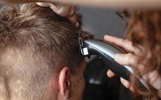 tagliando i capelli con un rifinitore, il parrucchiere si rade i capelli foto