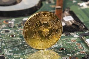 btc bitcoin moneta d'oro sul primo piano della scheda madre foto