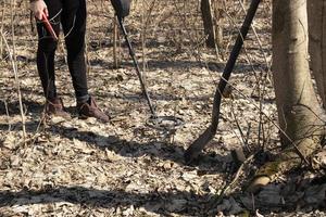 ragazza che cammina nella foresta con un metal detector, cerca il tesoro della moneta foto