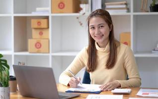 piccolo imprenditore PMI freelance, ritratto di giovane donna asiatica che lavora a casa in ufficio, scatola di consegna di imballaggi di marketing online, concetto di business di e-commerce. foto