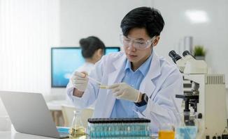 laboratorio di ricerca medica ritratto di un bel scienziato maschio che utilizza un computer tablet digitale, analizzando sostanze biochimiche liquide in un pallone da laboratorio. foto