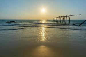 tramonto e riflessi dal mare, ponti di legno in decomposizione, spiaggia di khao pi lai phang nga, tailandia foto