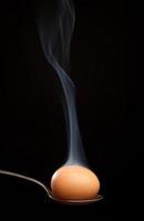 uovo marrone avvolto nel fumo in un cucchiaio d'argento foto