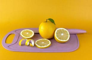 limone con foglia verde e fette di limone, bucce sul tagliere rosa foto