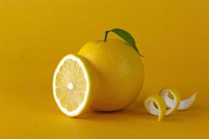 un frutto giallo limone con foglia e fetta di buccia isolato su sfondo giallo. una posizione creativa del concept design del limone per frutta sana foto