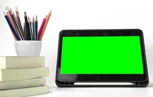 materiali didattici nella scatola, con schermo verde ipad e libri isolati su sfondo bianco. torna a modelli di concetto di poster di scuola foto