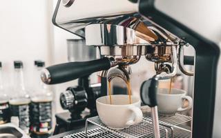 estrazione del caffè dalla macchina da caffè professionale barista.espresso che versa da una macchina da caffè in una tazza di caffè in una caffetteria. foto