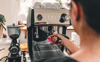 immagine ravvicinata di un barista che lavora a fare il caffè con la macchina da caffè in una caffetteria foto