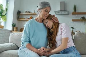 donna anziana che consola la figlia triste mentre è seduta sul divano insieme foto