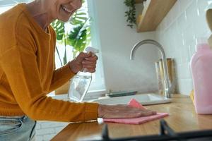 primo piano di una donna anziana sicura che riordina il bancone della cucina e sorride foto