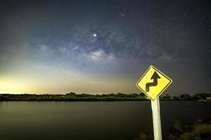 cartelli, cartelli, attenzione alle curve di notte, dietro il cartello, con la via lattea. foto