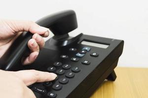 primo piano delle mani della donna tramite telefono sul tavolo da ufficio in legno foto