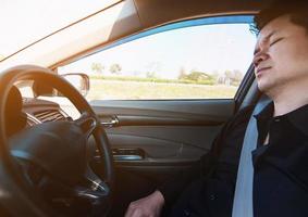 l'uomo dorme in macchina durante la guida su strada - le persone hanno provato da un lungo viaggio in auto e dal concetto di traffico foto