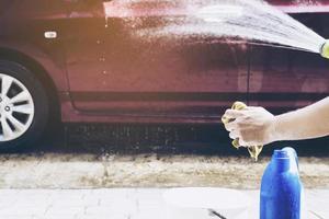 l'uomo prepara l'acqua dello shampoo per lavare l'auto utilizzando - concetto di pulizia dell'auto della gente di casa foto