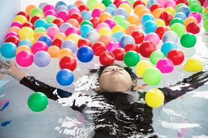 ragazzo che gioca con la palla colorata nel giocattolo della piccola piscina - ragazzo felice nel concetto del giocattolo della piscina d'acqua foto