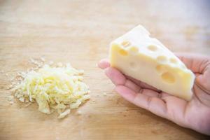 donna che prepara il formaggio per cucinare usando la grattugia in cucina - persone che producono cibo con il concetto di formaggio foto