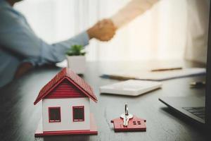 agente immobiliare che stringe la mano al cliente dopo la firma del contratto e l'affare concluso per il trasferimento del diritto di proprietà. uomo broker agente immobiliare agente immobiliare stringere la mano a clienti felici proprietari di case foto