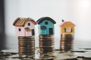 modello di casa e monete monete pile su sfondo sfocato tabella. piani di risparmio per casa, prestito, investimento, mutuo, finanza e banche sul concetto di casa. foto