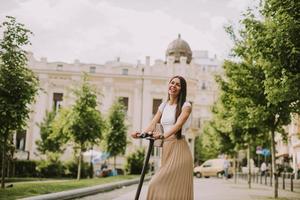 giovane donna in sella a uno scooter elettrico su una strada foto