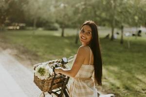 giovane donna con fiori nel cestino della bici elettrica foto