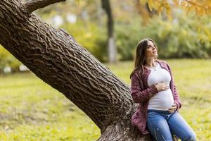 giovane donna incinta nel parco d'autunno foto